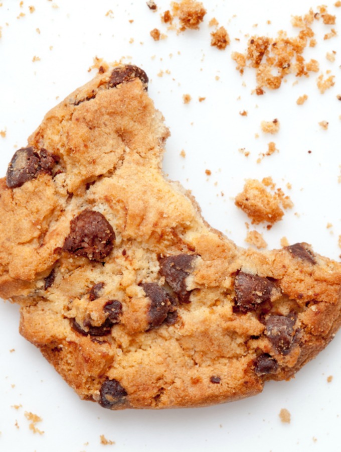 Close up of an half eaten cookie with crumb against a white background